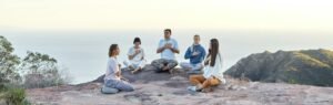 group of people sitting in circle and meditating by the seaside